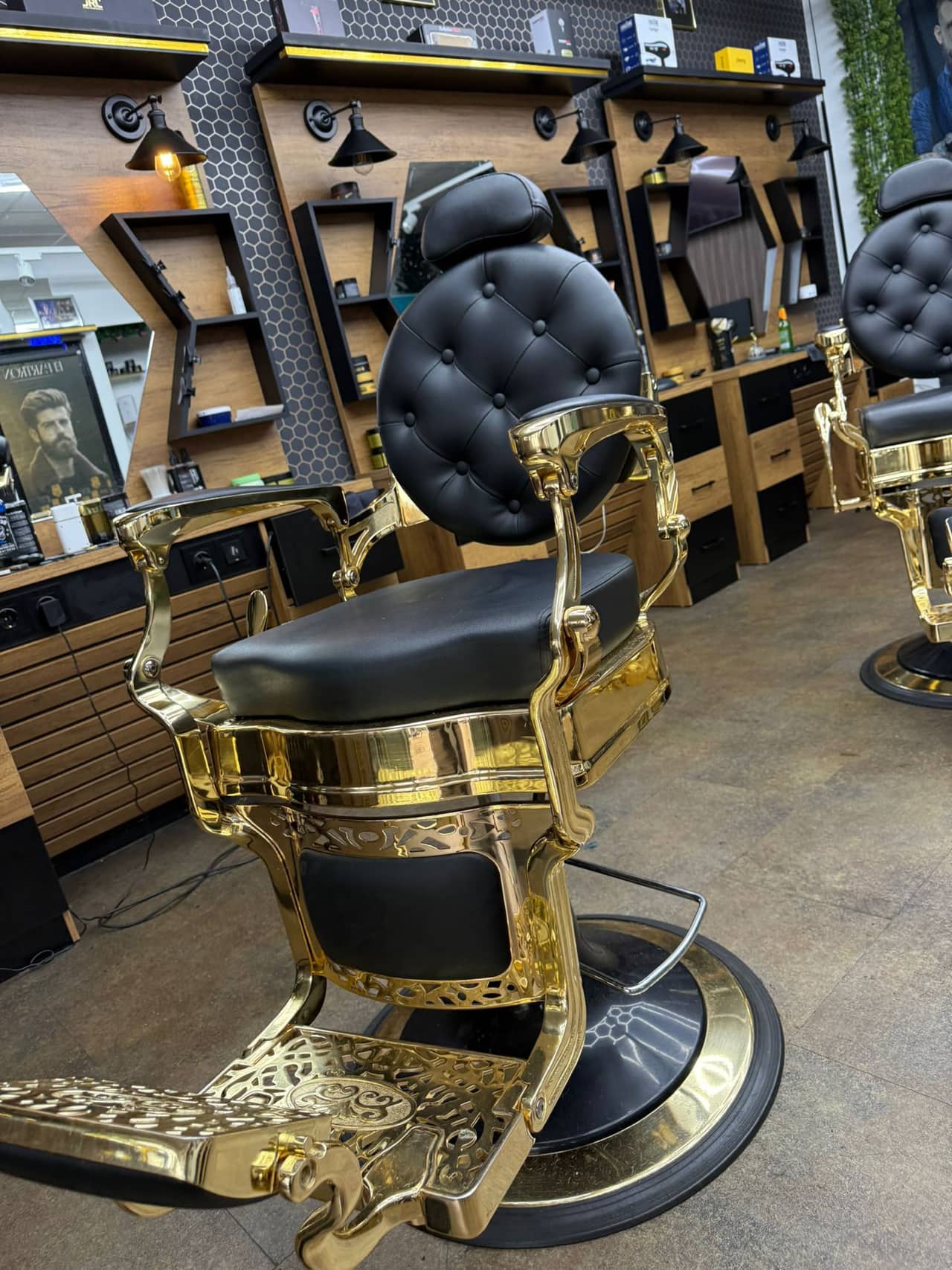 Een gouden kappersstoel met zwarte leren zitting, van dichtbij.