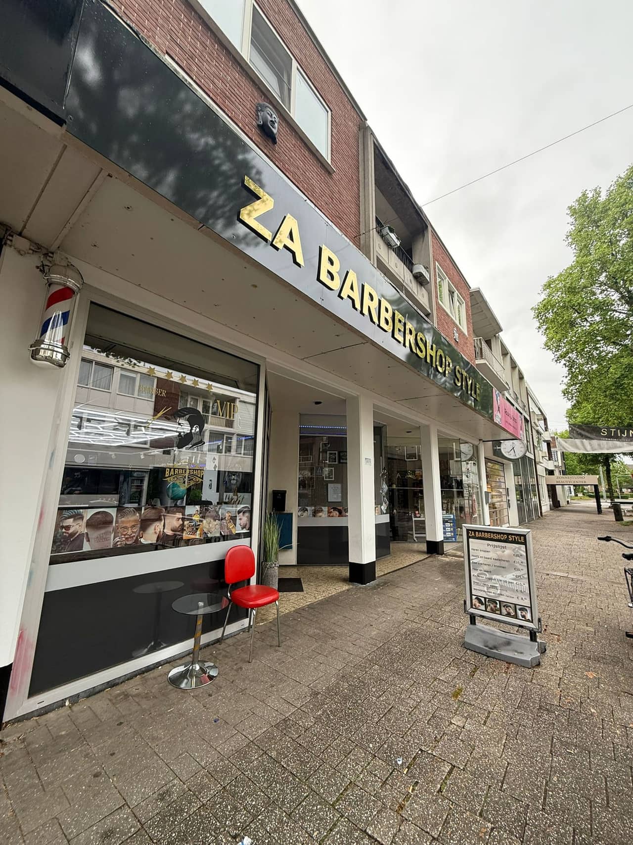 De gevel aan de Hoofdstraat, met het gouden bord en een barberspaal naast de deur.