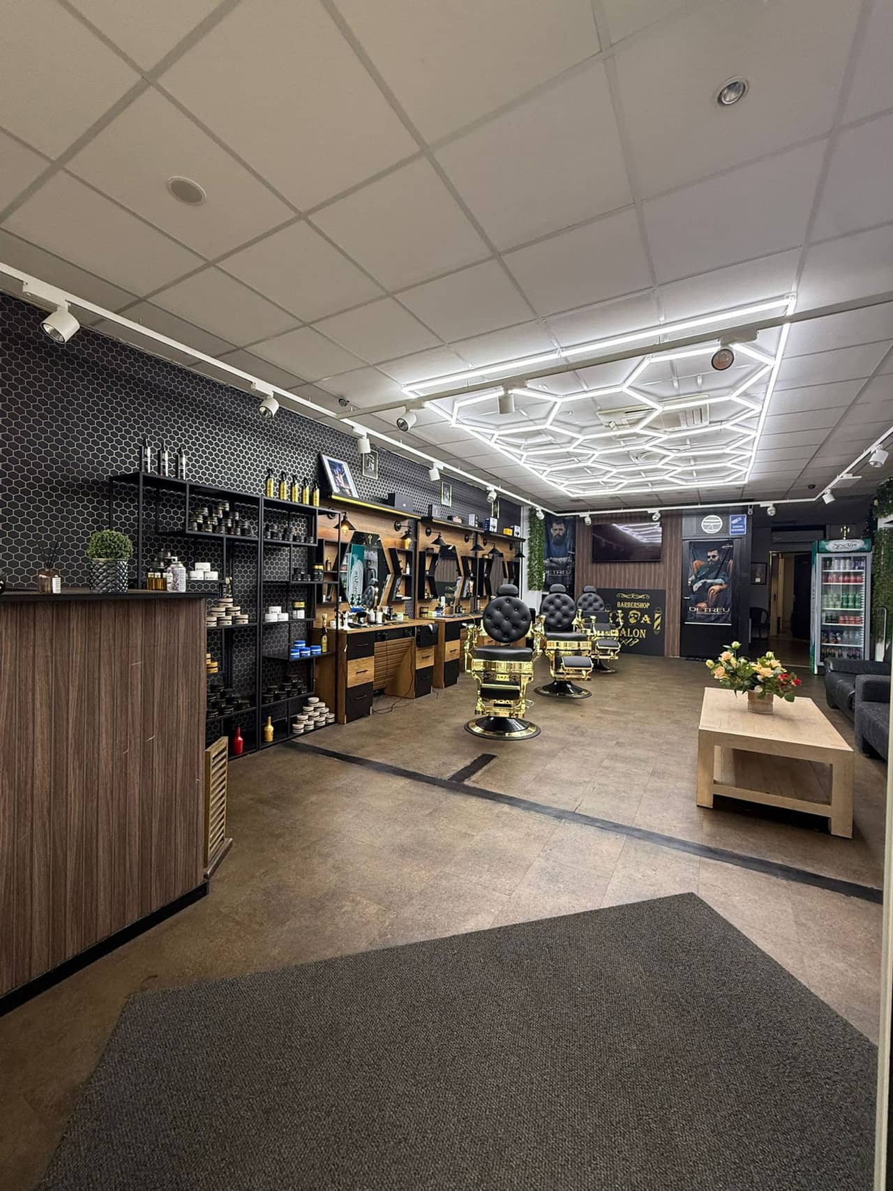 De zaak van binnen, gezien vanaf de deur: de balie, de schappen met producten en de kappersstoelen.
